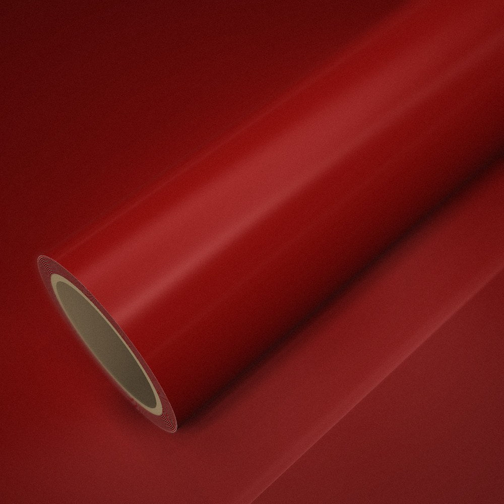 Rouleau de vinyle rouge brillant posé sur une feuille du même vinyle
