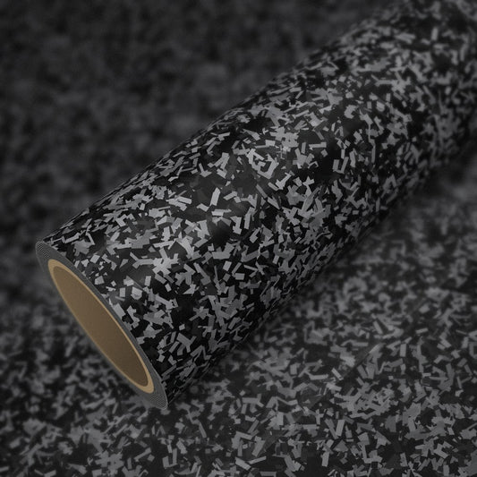 Rouleau de vinyle carbone forgé argent brillant posé sur une feuille du même vinyle