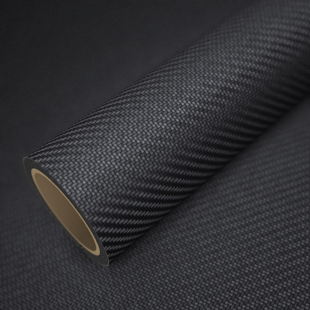 Rouleau de vinyle carbone noir mat posé sur une feuille du même vinyle