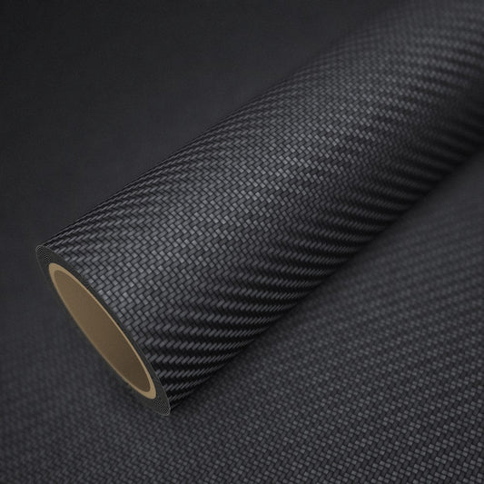Rouleau de vinyle carbone noir mat posé sur une feuille du même vinyle
