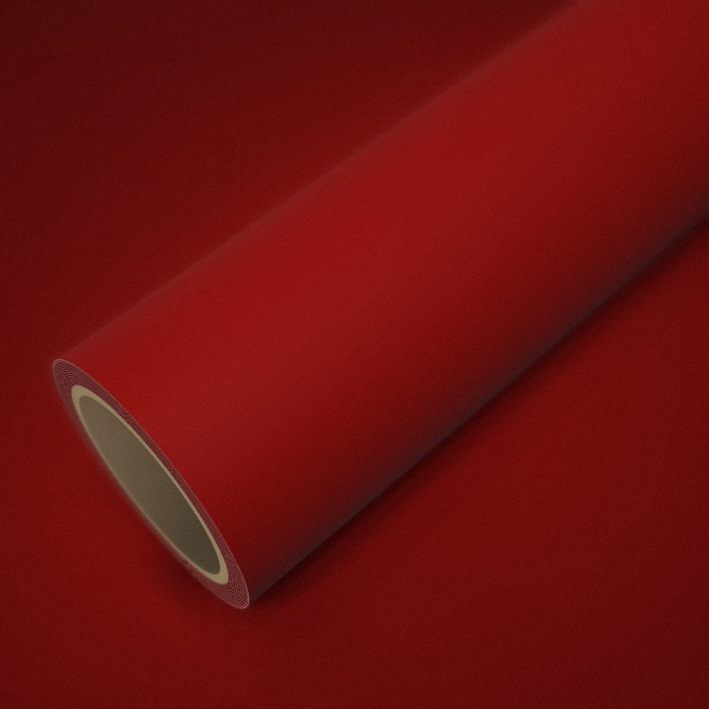 Rouleau de vinyle rouge mat posé sur une feuille du même vinyle