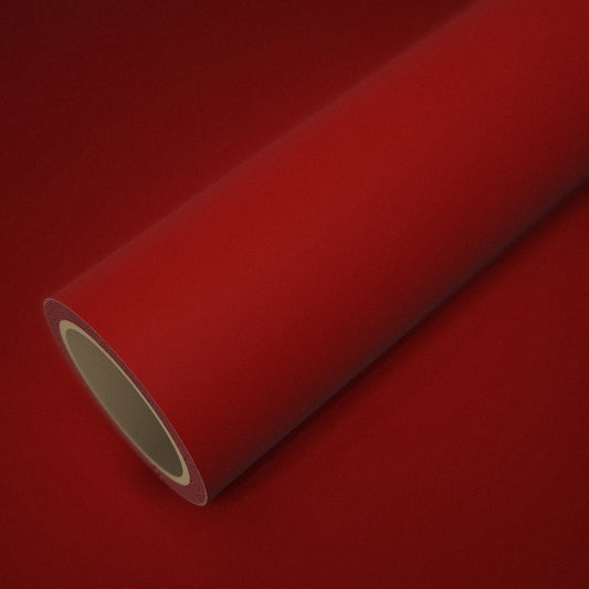 Rouleau de vinyle rouge mat posé sur une feuille du même vinyle