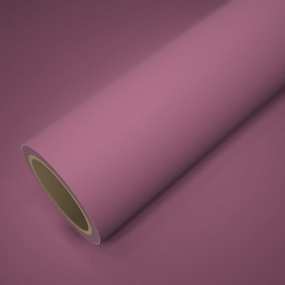 Rouleau de vinyle rose mat posé sur une feuille du même vinyle
