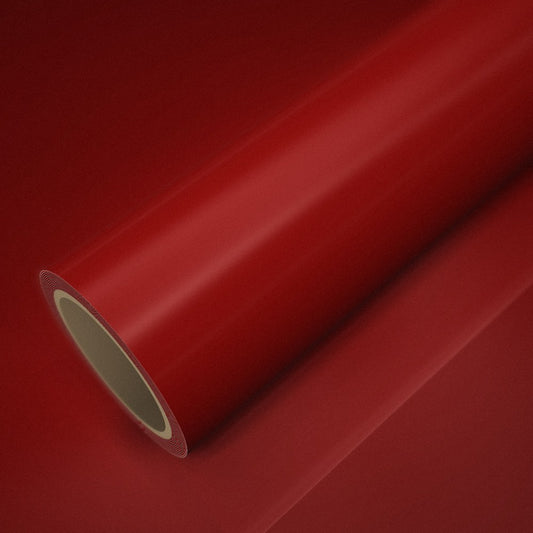 Rouleau de vinyle rouge brillant posé sur une feuille du même vinyle