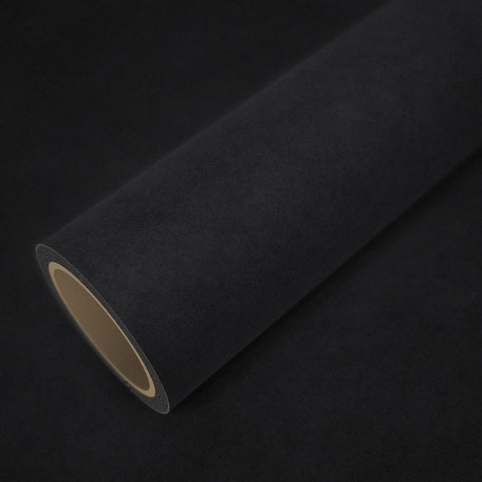 Rouleau de vinyle effet alcantara noir posé sur une feuille du même vinyle